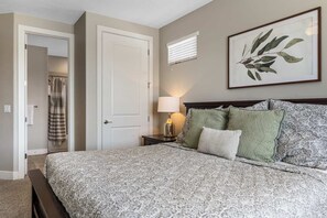 A bedroom with a patterned bedspread, a bedside lamp, and a framed botanical print on the wall. - Red Sand Hideaway #119 5 Bedroom Home (Ivins)