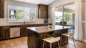 A modern kitchen with a central island, wooden cabinets, and a large window. - Red Sand Hideaway #119 5 Bedroom Home (Ivins)