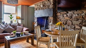 A cozy living room with a stone fireplace, wooden furniture, and a comfortable seating area.