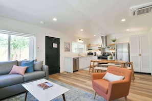 A modern living room with a sofa, coffee table, and a dining area with a table and chairs. - Moab Inn Towner #3 - Heart of Downtown (Moab)