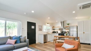 A modern living room with a sofa, coffee table, and a dining area with a table and chairs. - Moab Inn Towner #4 - Heart of Downtown (Moab)