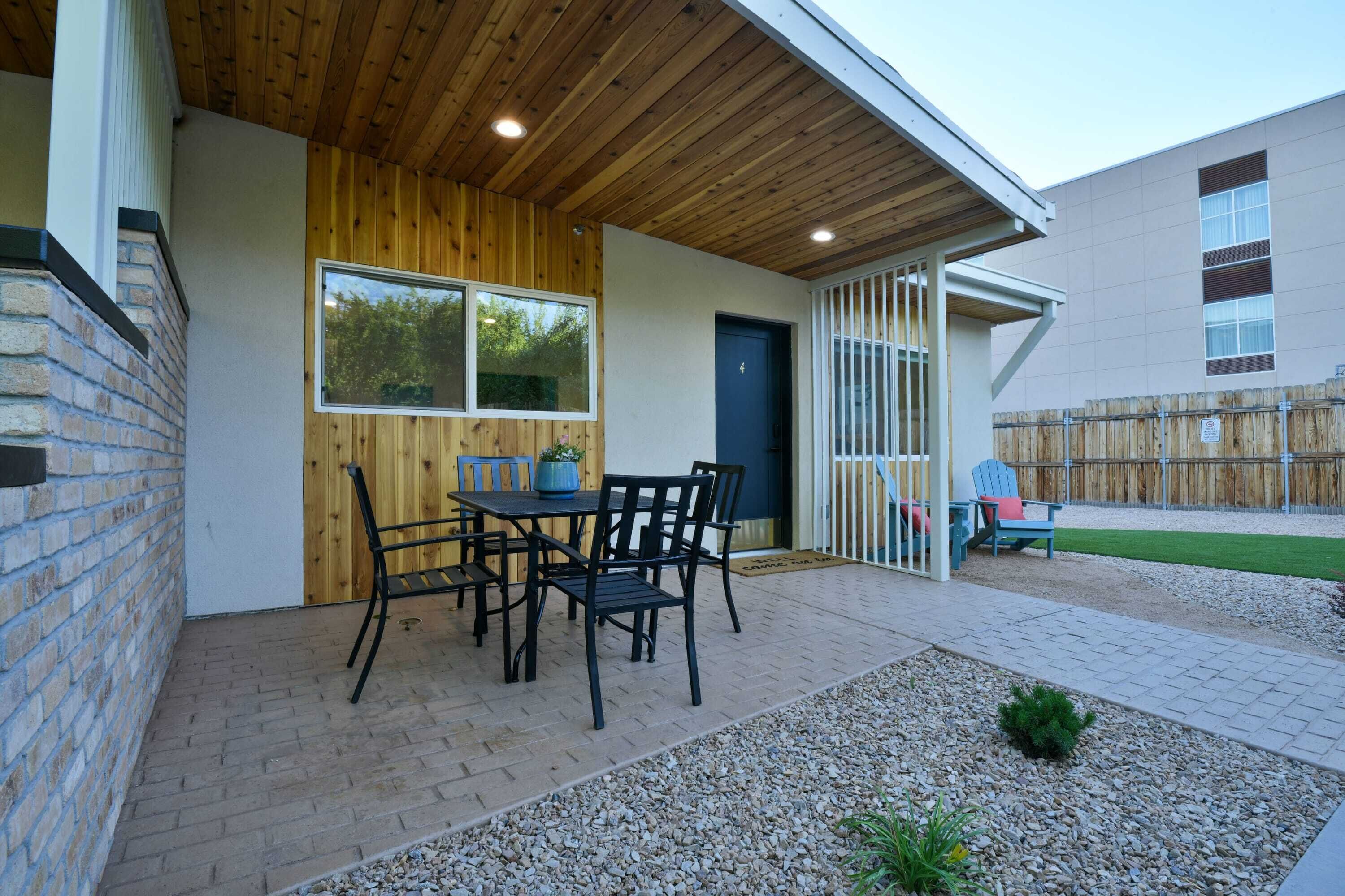 Un patio con piso de ladrillo, techo de madera y una mesa con sillas.