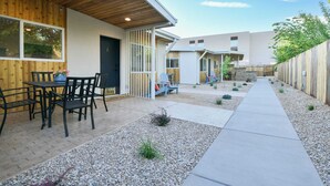 A modern outdoor patio area with a wooden deck, seating, and a pathway. - Moab Inn Towner #4 - Heart of Downtown (Moab)