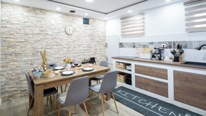 Cozinha moderna com parede de pedra, armários de madeira e área de jantar com mesa posta para quatro pessoas.