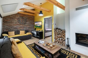 A living room with a sofa, coffee table, fireplace, and a brick wall. - Cozy House In Nature With Hot Tub (Jalžabet)