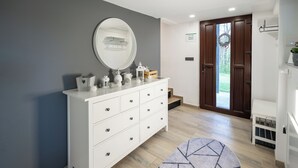Uma casa de banho moderna com uma toucador branca, um espelho grande e uma porta de madeira que dá para uma varanda.