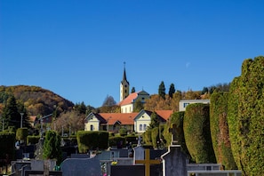 En kirkegård med velplejede hække, en kirke med et højt tårn og en bakke i baggrunden.