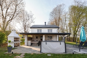 Talo, jossa on patio, ulkotila istumiseen ja grillauspaikka.