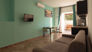 Una sala de estar con un sofá, un televisor, un cuadro y un comedor con una mesa y sillas.