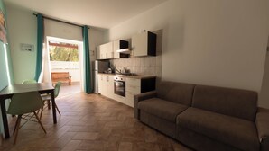 Cocina compacta con comedor, sofá y puerta corredera de cristal que da a un área de estar al aire libre.