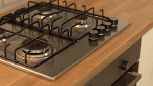 Una cocina con estufa a gas, horno y encimera de madera.