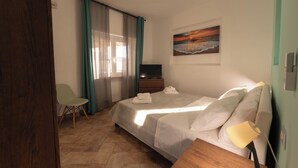 Una habitación de hotel con cama, una silla, televisión y un cuadro en la pared.