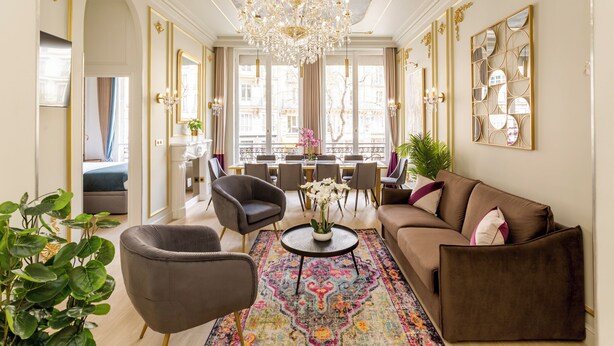 Ein luxuriöses Wohnzimmer mit einer Chandelier, Sofas, Sesseln und einem Essbereich mit Blick.