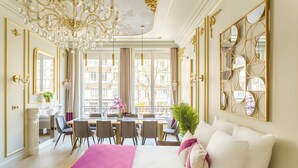 Ein luxuriöses Hotelzimmer mit einem großen Bett, einem Essbereich und Blick auf die Stadt.