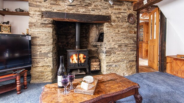 Una sala de estar acogedora con chimenea de piedra, un televisor y una mesa con copas de vino y queso.