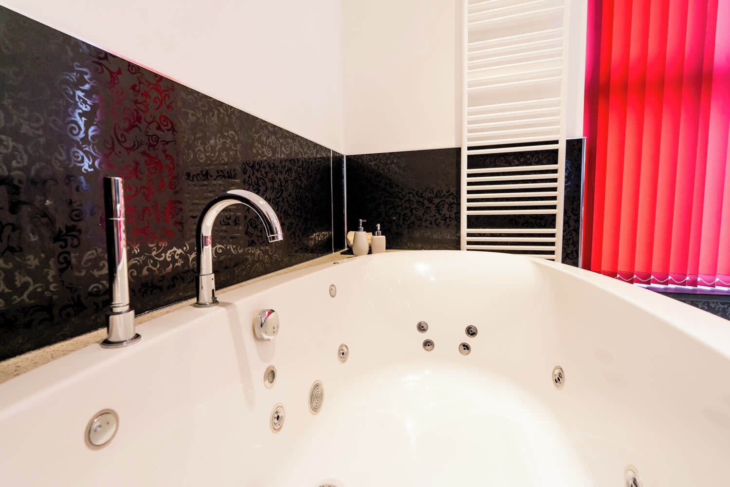 Ein modernes Badezimmer mit einer freistehenden Badewanne, einem Wandarmaturen-Set und einem Fenster mit vertikalen Rollläden.