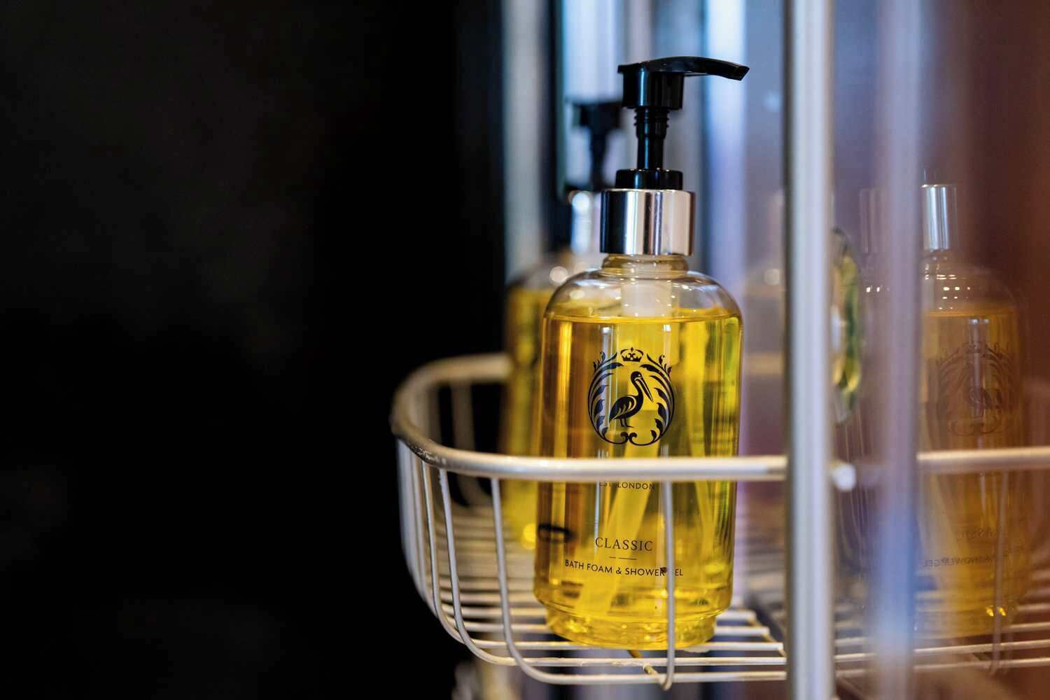 Ein Badezimmerschrank mit einer Flasche mit dem Aufdruck 'CLASSIC BATH FOAM & SHOWER BOWL' und einer Pumpspenderflasche.