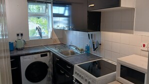 A compact kitchen with a washing machine, a microwave, a stove, and a sink. - Cosy 1-bed Apartment in Swindon, Private Parking (Swindon)