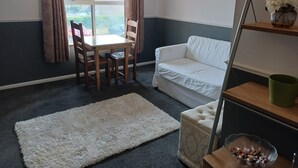 A room with a dining table and chairs, a white sofa, a white rug, and a window with curtains. - Cosy 1-bed Apartment in Swindon, Private Parking (Swindon)