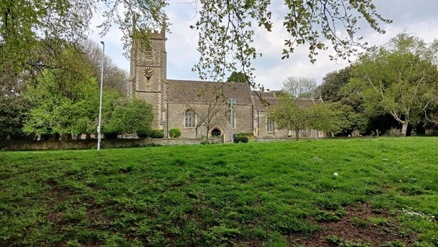 A church with a clock tower, surrounded by a grassy field and trees. - Cosy 1-bed Apartment in Swindon, Private Parking (Swindon)