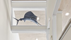 A staircase with a modern design, a dining area with a table and chairs, and a ceiling with a mounted fish sculpture. - The Hamptons, Oceanfront Duplex in Atlantic Beach, NC! (Atlantic Beach)