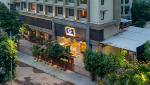 Um hotel com vários andares, um letreiro G HOTEL em destaque e um letreiro C HOTEL visível.