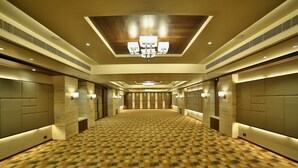 Um corredor de hotel com carpete estampado, iluminação embutida e um candelabro.