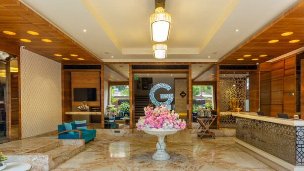 Um hall de entrada com balcão de recepção, uma grande peça central decorativa e uma área de estar com sofás azuis.