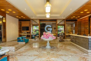 Eine Lobby mit einer Rezeption, einem großen Dekorationsobjekt und einer Sitzecke mit blauen Sofas.