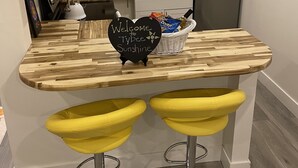 Una cucina moderna con un piano di lavoro in legno, un lavello, un frigorifero e due sgabelli gialli.