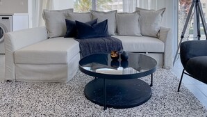 Un salon moderne avec un canapé d’angle, une table basse en verre et un lampadaire.