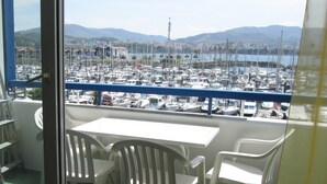Un balcón con mesa y sillas, con vista a un puerto deportivo lleno de barcos.