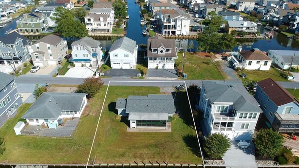 An aerial view of a residential area with houses, a dock, and a canal. - Waterfront Rancher in South Bethany (Bethany Beach)