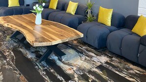 Un salon moderne avec un canapé d’angle, une table basse en bois et un luminaire fixé au mur.
