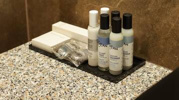A bathroom counter with toiletries including bottles of body wash and lotion, a toothbrush, and a razor.