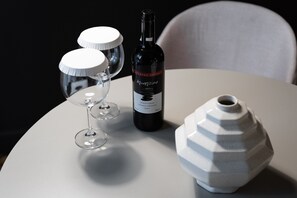 A table with a wine bottle, two wine glasses, and a ceramic vase.