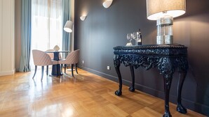 Ein Zimmer mit dunkler Wand, Holzboden, einem Tisch mit Lampe und zwei Stühlen.