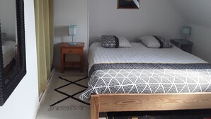 Une chambre à coucher comprenant un lit, une table de chevet, une lampe et un tableau encadré accroché au mur.