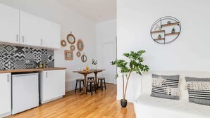 A modern kitchen with white cabinets, a wooden countertop, and a dining area with stools. - Appartement central a deux pas des Halles a Paris (Paris)