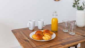 A breakfast table with croissants, a juice bottle, and glasses, surrounded by various wall-mounted mirrors. - Appartement central a deux pas des Halles a Paris (Paris)