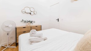 A minimalist bedroom with a bed, bedside fan, wooden nightstand, and wall decor. - Appartement central a deux pas des Halles a Paris (Paris)
