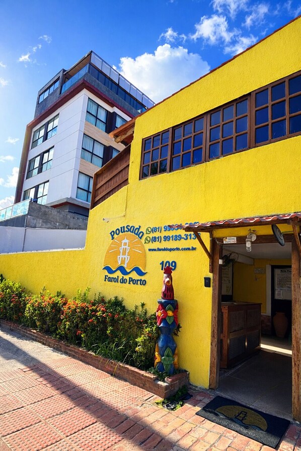 Un edificio amarillo con un cartel que dice 'Pousada 109 Faro do Porto' y una decoración de gallo.