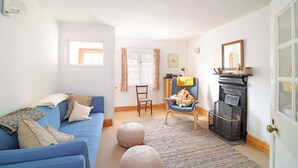 A cozy living room with a blue sofa, a wooden chair, a fireplace, and a patterned rug.