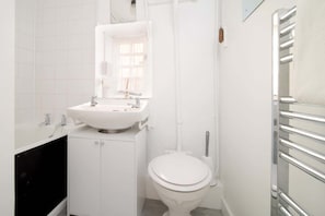 Ein modernes Badezimmer mit einem weißen Waschbecken, einer Toilette und einer Badewanne.