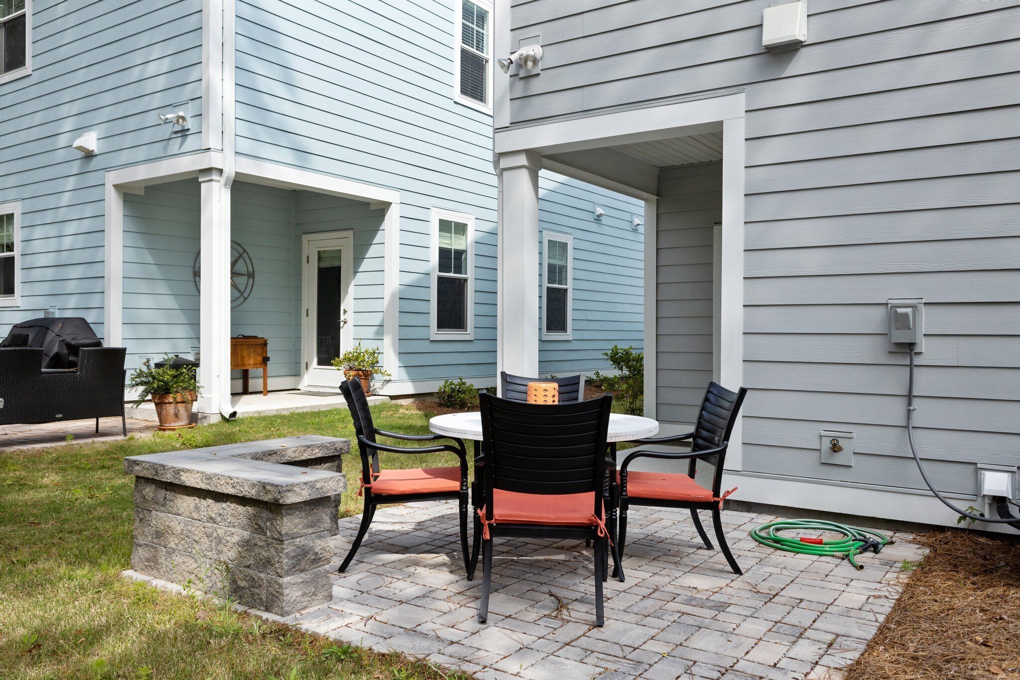 A patio with a stone bench, two chairs, and a table.