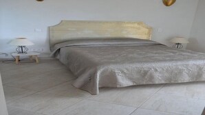 Un dormitorio con una cama, dos mesitas de noche y lámparas fijadas a la pared.