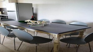 Comedor con una mesa rectangular, seis sillas, una botella de vino y un plato decorativo.