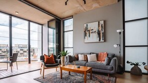 Ein modernes Wohnzimmer mit einem grauen Sofa, einem Holztisch und einem gemusterten Teppich.