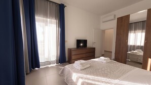 Ein Hotelzimmer mit Bett, Schminktisch, Fernseher und Spiegel.