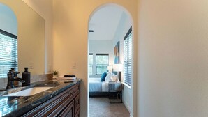 A narrow hallway with a bathroom on the right, featuring a sink, mirror, and towel rack. - Relax & Play in Style: Luxury Home w/ Infinity Pool, Game Room & Alfresco Dining (Jonestown)